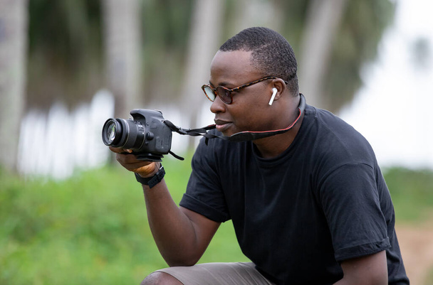Mladý Afričan praktikuje fotografování pro zábavu a s velkým nasazením v africké vesnici. - Fotografie, Obrázek