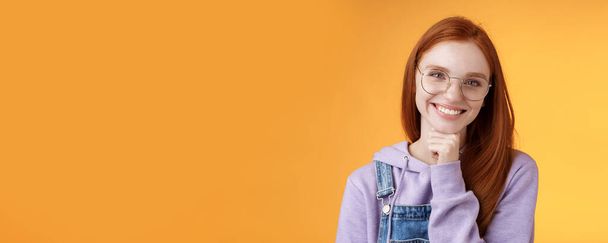 Creative outgoing young charismatic redhead female coworker discuss casual staff smiling laughing happily have pleasant conversation look camera amused tender touch chin, orange background. - Photo, Image