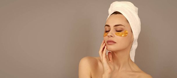 Eye patches, patch under eyes. Beautiful woman isolated face portrait, banner with mock up copy space. Skin that speaks. cosmetology. young woman in terry towel use patch. beauty day in spa - Photo, Image