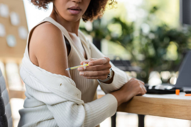 Vista ritagliata di donna d'affari afro-americana che fa l'iniezione di insulina in ufficio  - Foto, immagini