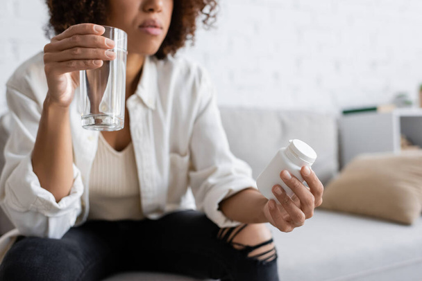 Oříznutý pohled na africkou americkou ženu s cukrovkou držící sklenici s pilulkami a sklenicí vody doma  - Fotografie, Obrázek