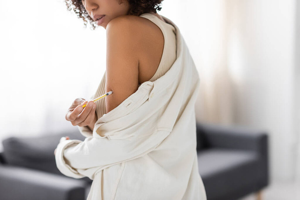 Vista ritagliata della donna afro-americana con diabete che fa l'iniezione di insulina in soggiorno  - Foto, immagini