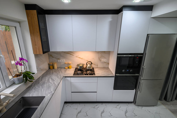 Een ruime en bijgewerkte keuken met zwart-wit kleurenschema, met uitschuifbare planken voor handige opslag en organisatie, hoge hoek uitzicht - Foto, afbeelding