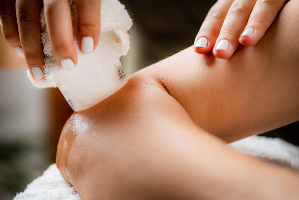 Ice Massage for Painful Elbow. Hands of a therapist placing ice directly onto a painful elbow to relieve pain, reduce inflammation and swelling and promote healing. - Photo, Image