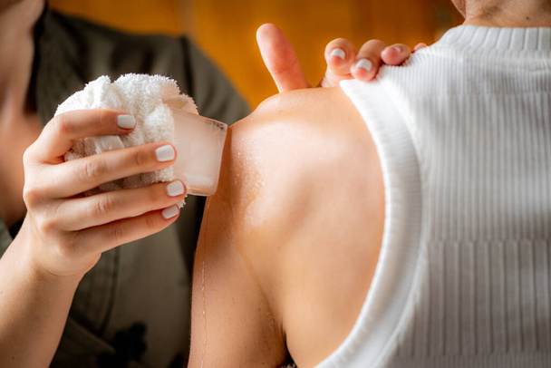 Schulterkryotherapie-Eismassage. Hände eines Therapeuten legen Eis direkt auf eine schmerzhafte Schulter, um Schmerzen zu lindern, Entzündungen und Schwellungen zu verringern und die Heilung zu fördern. - Foto, Bild