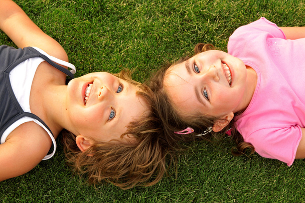 Dos chicas sonrientes tumbadas en la hierba
 - Foto, imagen