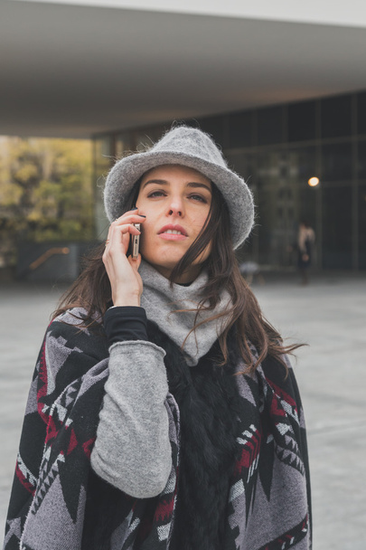 Mooie jonge brunette praten over telefoon in de straten van de stad - Foto, afbeelding