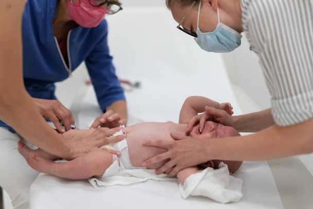 Bebê sendo vacinado por pediatra na presença de sua mãe. Vacinação preventiva contra a difteria, tosse convulsa, tétano, hepatite, hemophilus influenzae, pneumococo, poliomielite. - Foto, Imagem