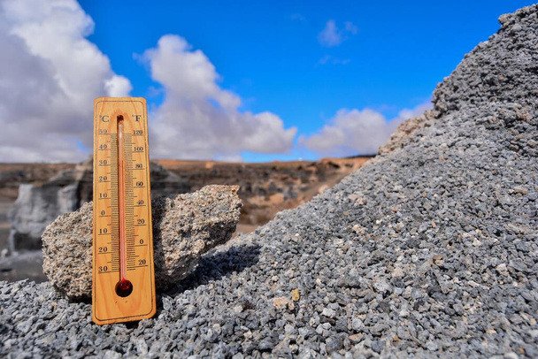 een lage hoek opname van een enkele houten thermometer op een achtergrond van een berg  - Foto, afbeelding