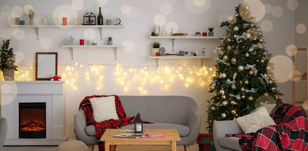 輝くガーランド、クリスマスツリー、暖炉とソファ付きの光のリビングルームのインテリア - 写真・画像