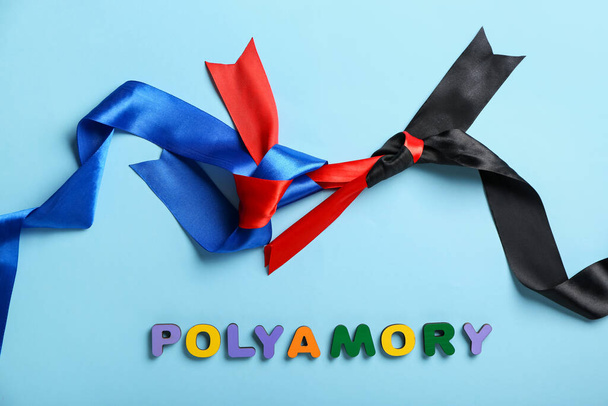 Wort POLYAMORY mit Schleifen auf blauem Hintergrund - Foto, Bild