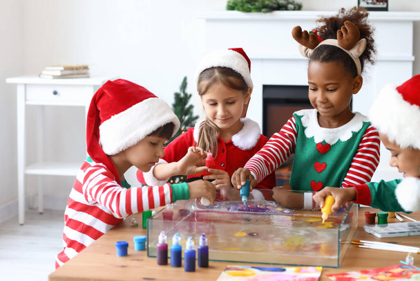 Małe dzieci w kostiumach świątecznych wylewanie farb do wody w warsztacie do malowania Ebru - Zdjęcie, obraz