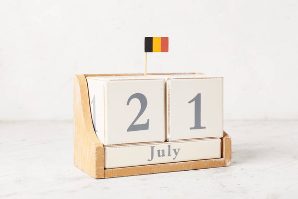 Kalendarz kostek i mała belgijska flaga na stole przy ścianie - Zdjęcie, obraz