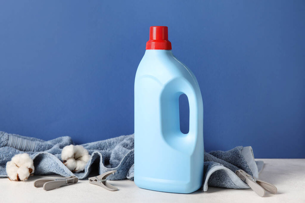Detergente de lavandaria e toalha com belas flores na mesa contra fundo azul - Foto, Imagem