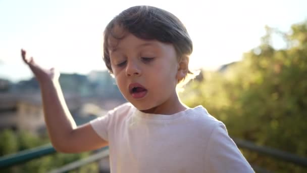 Ein kleiner Junge schlägt mit der Hand auf seinen eigenen Kopf. Porträt eines versehentlich im Freien stehenden Kindes. Oh kein Konzept - Filmmaterial, Video