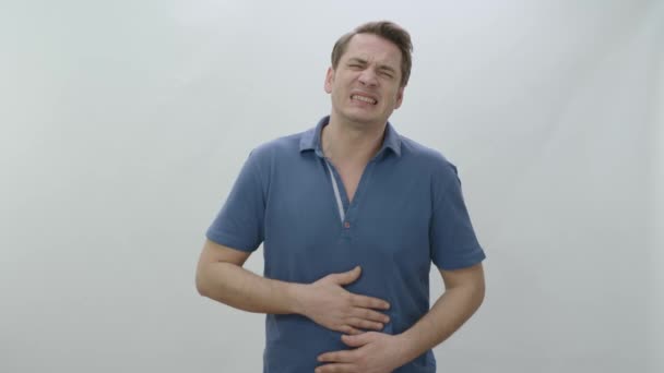 Man squeezing his stomach with his hands due to abdominal pain.A man with painful cramp in his sick, unhealthy stomach is squeezing his stomach and suffering from severe abdominal pain. - Footage, Video
