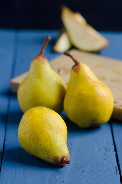 Yellow pears on a blue wooden table  - Fotó, kép