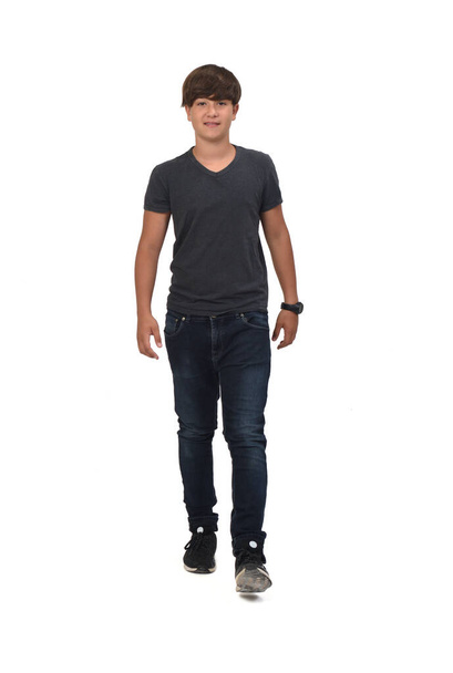 vista frontal de un retrato completo de un adolescente con jeans y zapatillas de deporte caminando sobre fondo blanco - Foto, imagen