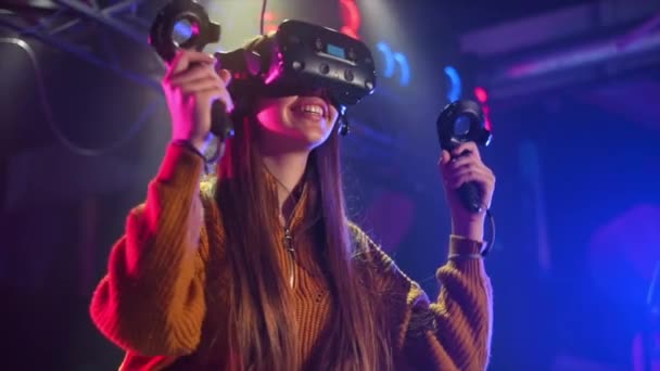 Une fille joyeuse et intéressée gagne sur le tapis roulant VR avec casque et contrôleurs. Mouvement lent - Séquence, vidéo