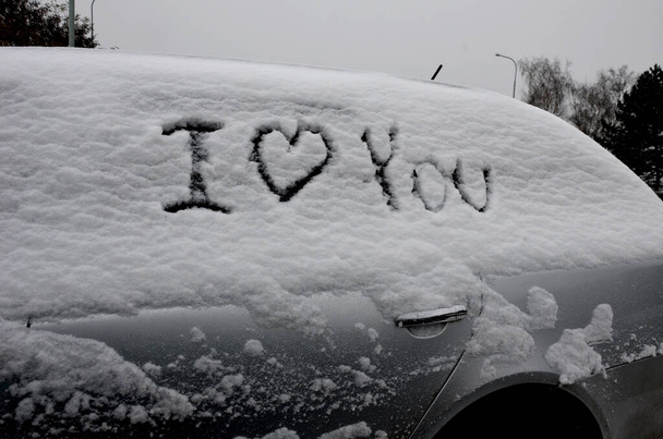 Ich liebe dich auf einem geparkten, schneebedeckten Fahrzeug. Ein Streich kann die Scheidung bedeuten. Alle verdächtigen sich gegenseitig der Untreue. Denken Sie darüber nach, bevor Sie das Fahrzeug jemandem unterschreiben. - Foto, Bild