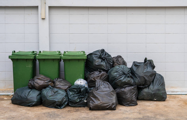 La basura en bolsas negras se coloca con contenedores de basura para ser separados en el sistema de gestión de residuos. - Foto, Imagen