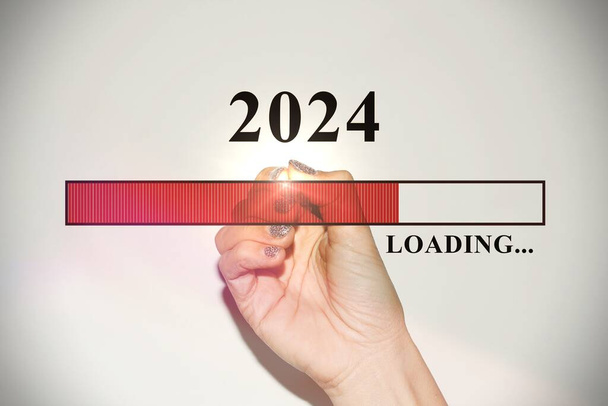 Mano de mujer con uñas de purpurina mostrando la barra de carga con el nuevo año 2024 - Foto, Imagen