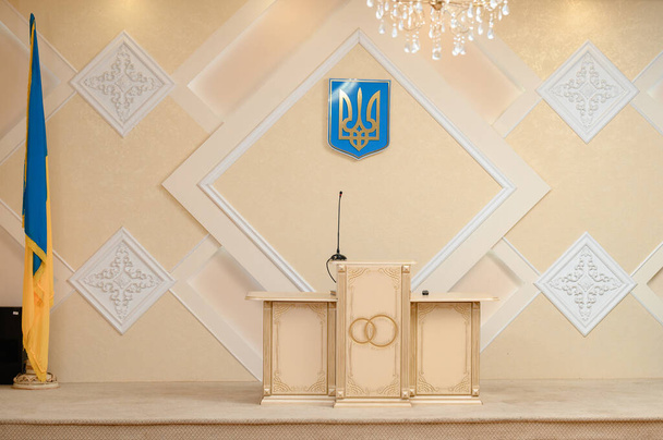 Ivano-Frankivsk, Ukrajna november 22, 2022: állami intézmény a házasság bejegyzésére, asztal és ukrán szimbólumok államiság, csarnok ünnepélyes események. - Fotó, kép