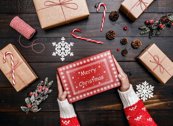 Руки показывают рождественский подарок. Деревянный фон с украшениями и подарками. Волшебное Рождество. - Фото, изображение