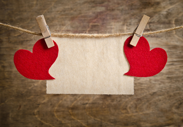 Two Red fabric hearts with sheet of paper hanging on the clothes - Фото, изображение
