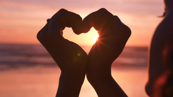 Love, heart and hands of woman at beach for freedom, support and happy, sign at sunset. Silhouette, nature and respect with girl on vacation for romance, inspiration and valentines day holiday. - Footage, Video