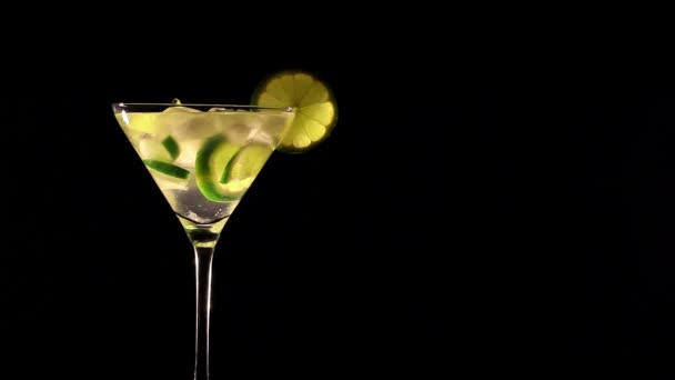 Roterende cocktail met limoen en ijs op zwarte achtergrond - Video
