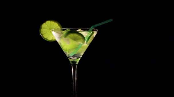 Roterende cocktail met limoen en ijs op zwarte achtergrond - Video