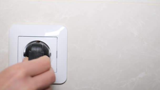 Handen van een vrouw die een elektrisch apparaat aanzet in een stopcontact. Huishoudelijke apparaten aanzetten vanaf het stopcontact. 4k video - Video
