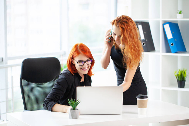 二人の赤髪の女性が現代のオフィスで一緒に働く. - 写真・画像