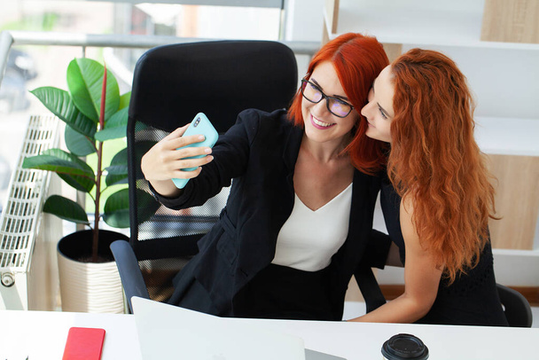 Zwei rothaarige Frauen arbeiten gemeinsam im modernen Büro. - Foto, Bild