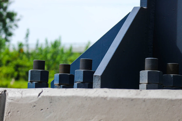 De blauwe bouten en moeren van de constructie met grote afmetingen zijn gemaakt van hoogwaardig staal, hoogwaardig trekstaal dat fungeert als anker om de sokkel fundering structuur te verbinden met de brug kolom stalen structuur. - Foto, afbeelding