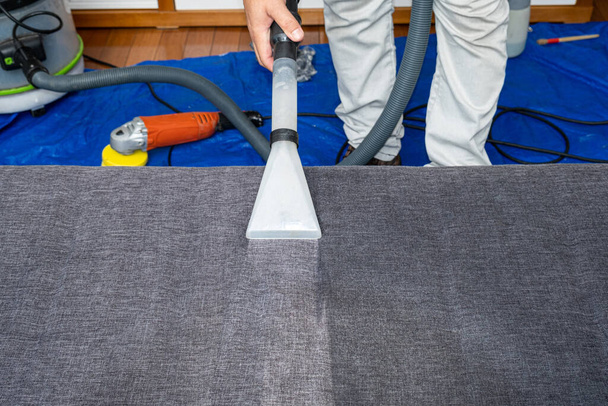 Man using a special vacuum to clean sofa cushions. - Photo, Image