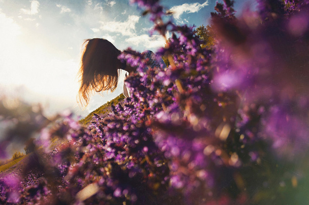 the girl is sitting on a glade of flowers - Photo, image