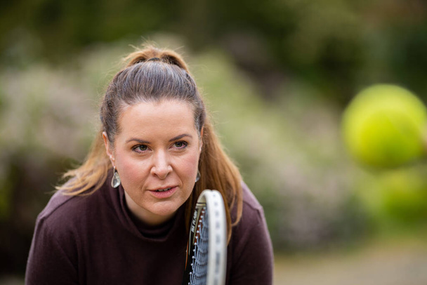 jugadora de tenis que practica de frente y golpea pelotas de tenis en una cancha de hierba en Inglaterra - Foto, Imagen