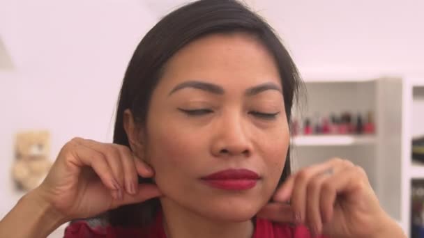PORTRAIT: Snímek hlavy krásné asijské ženy, která si dává masáž obličeje. Hezká mladá dáma při relaxaci ošetření obličeje pro uvolnění svalů obličeje. Žena, která má krásnou vlastní terapii. - Záběry, video