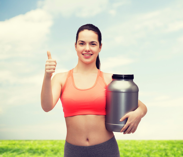 teenage girl with jar of protein showing thumbs up - Foto, imagen