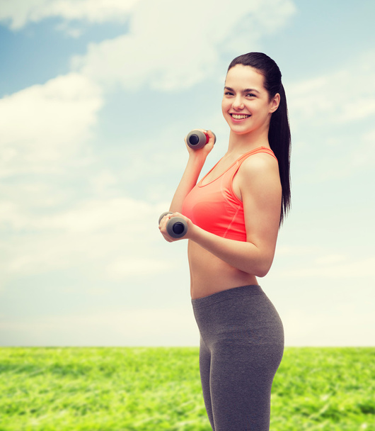 young sporty woman with light dumbbells - Foto, imagen