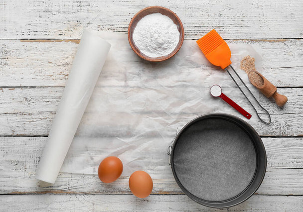 Papier à pâtisserie avec fournitures de cuisine, farine et oeufs sur fond de bois blanc - Photo, image
