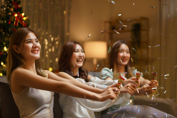 New Year celebration concept, Young beautiful group shooting confetti poppers with fun in party. - Photo, Image