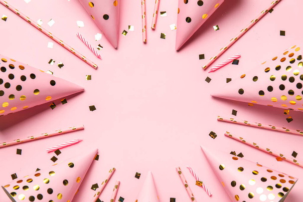 Frame gemaakt van feestmutsen, confetti en rietjes op roze ondergrond - Foto, afbeelding