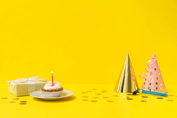 Juhlahatut, lahja, syntymäpäiväkakku ja konfetti keltaisella taustalla - Valokuva, kuva