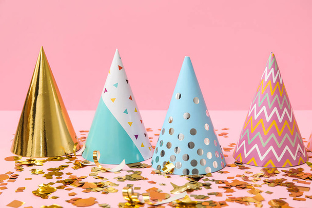 Sombreros de fiesta y confeti sobre fondo rosa - Foto, Imagen
