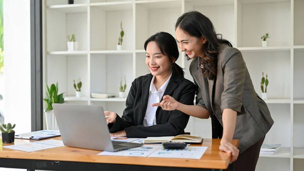 Aantrekkelijke en professionele Aziatische vrouwelijke baas is het trainen en coachen van haar nieuwe assistent, samen te werken in het kantoor. - Foto, afbeelding