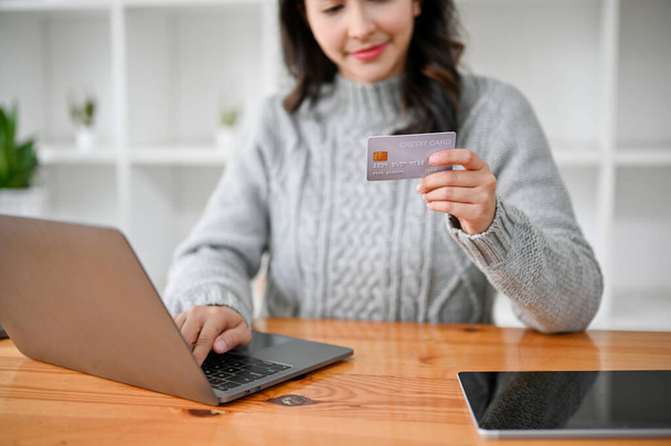 Jovem mulher asiática atraente usando computador portátil, segurando um cartão de crédito, registre o cartão de crédito no site de compras, pagamento on-line. - Foto, Imagem