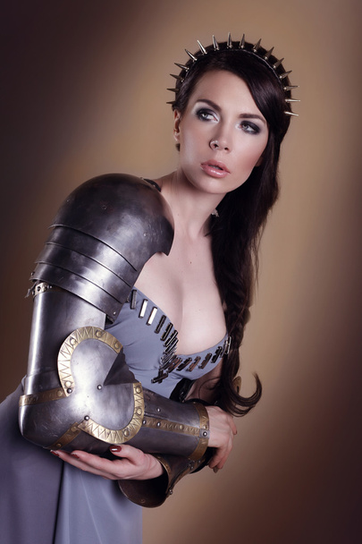 portrait of a beautiful lady warrior, dark-haired girl in a gray dress. bright makeup, hairstyle, spikes - Valokuva, kuva